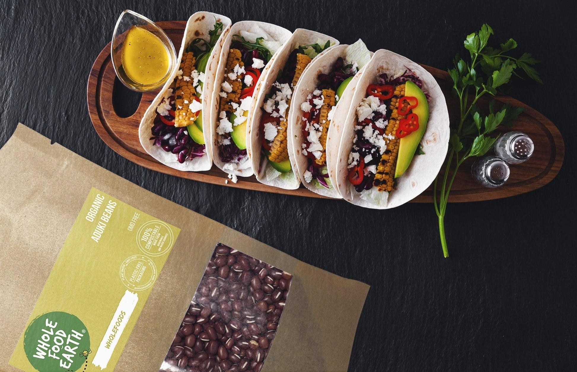 Organic Aduki Beans from Whole Food Earth, GMO-free, displayed in a bowl with some beans spilled on a wooden surface.