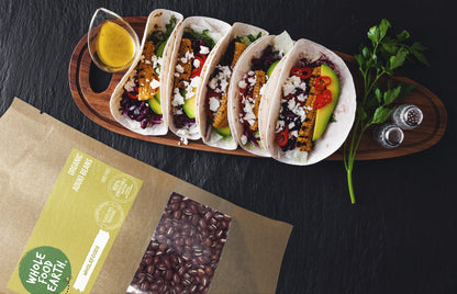 Organic Aduki Beans from Whole Food Earth, GMO-free, displayed in a bowl with some beans spilled on a wooden surface.