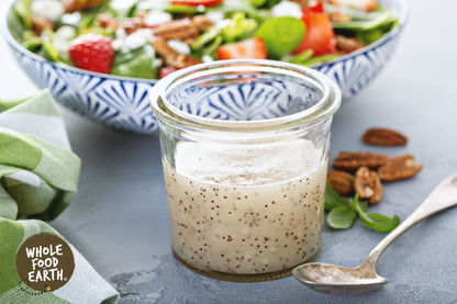 Unwashed raw poppy seeds from Whole Food Earth, GMO-free in a clear container, showing small black seeds.