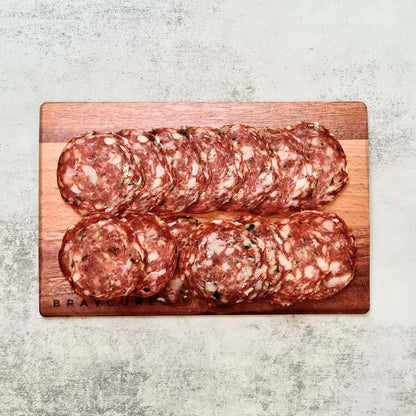 Sliced Bray Cured Wild Garlic Salami on a charcuterie board with cheese and crackers, showcasing its marbled texture and wild garlic flavor.