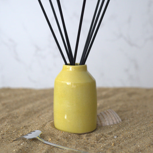 Sun yellow reed diffuser from Katie L Thompson Designs with a square glass bottle and reed sticks for home fragrance.