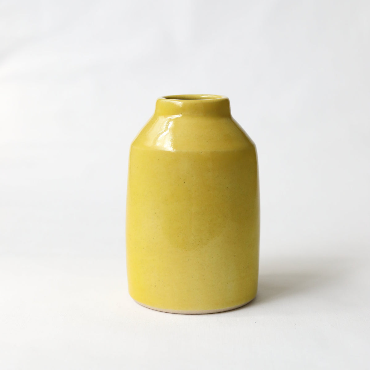 Sun yellow classic bud vase by Katie L Thompson Designs on a white background, ideal for holding small floral arrangements.