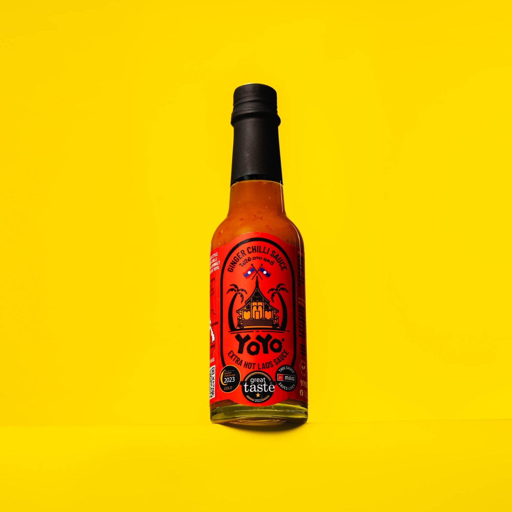 Bottle of YoYo Laos Sauce Extra Hot Ginger Chilli Sauce, signature spicy condiment with vibrant label and bright red sauce inside.