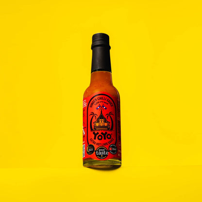 Bottle of YoYo Laos Sauce Extra Hot Ginger Chilli Sauce, signature spicy condiment with vibrant label and bright red sauce inside.