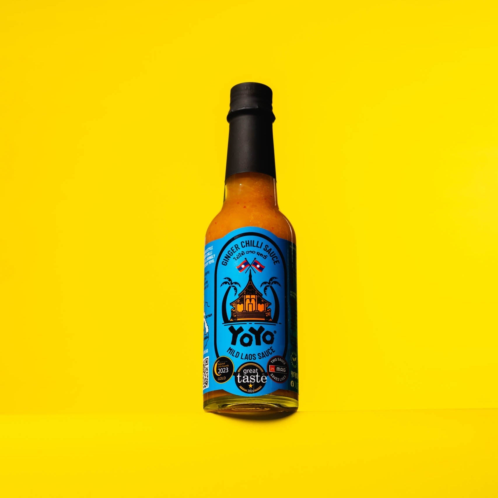 Bottle of YoYo Laos Sauce Mild Ginger Chilli Sauce, signature sauce with ginger and chilli flavor in a clear glass bottle.